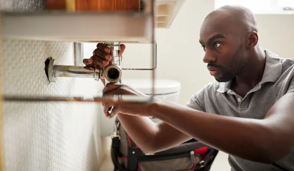 a male plumber fixing a pipe connection
